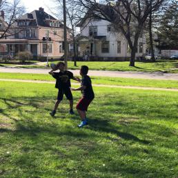 Two young boys toss a football in the grass
